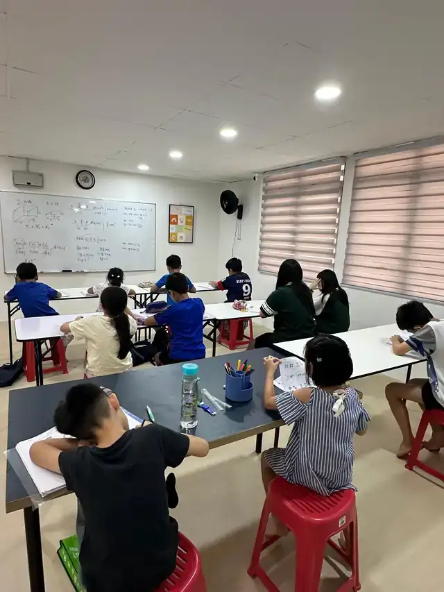 老师在课室前讲解数学，孩子们坐在位子上做题
