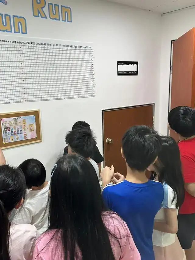 孩子们围在积分墙前面看自己的进度